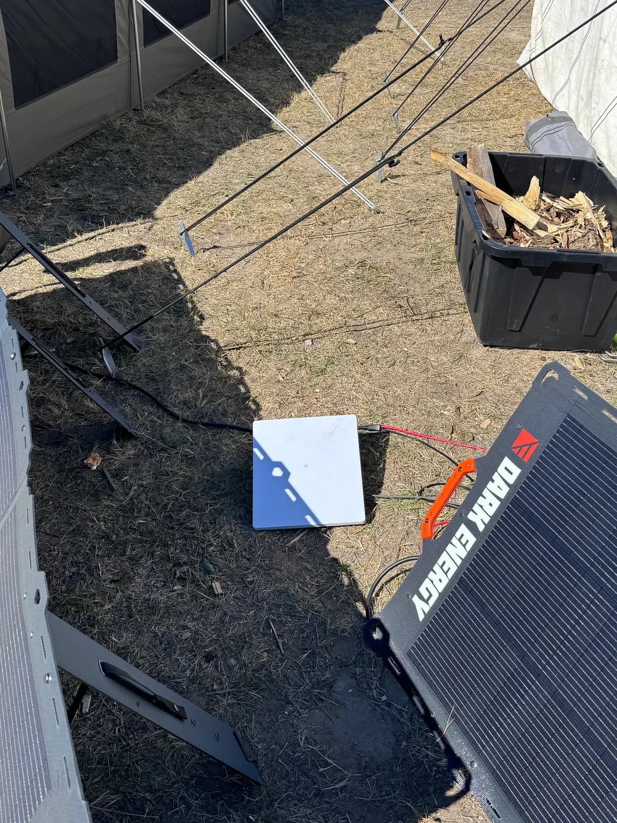 A Starlink Mini dish on the ground next to a Dark Energy solar panel.